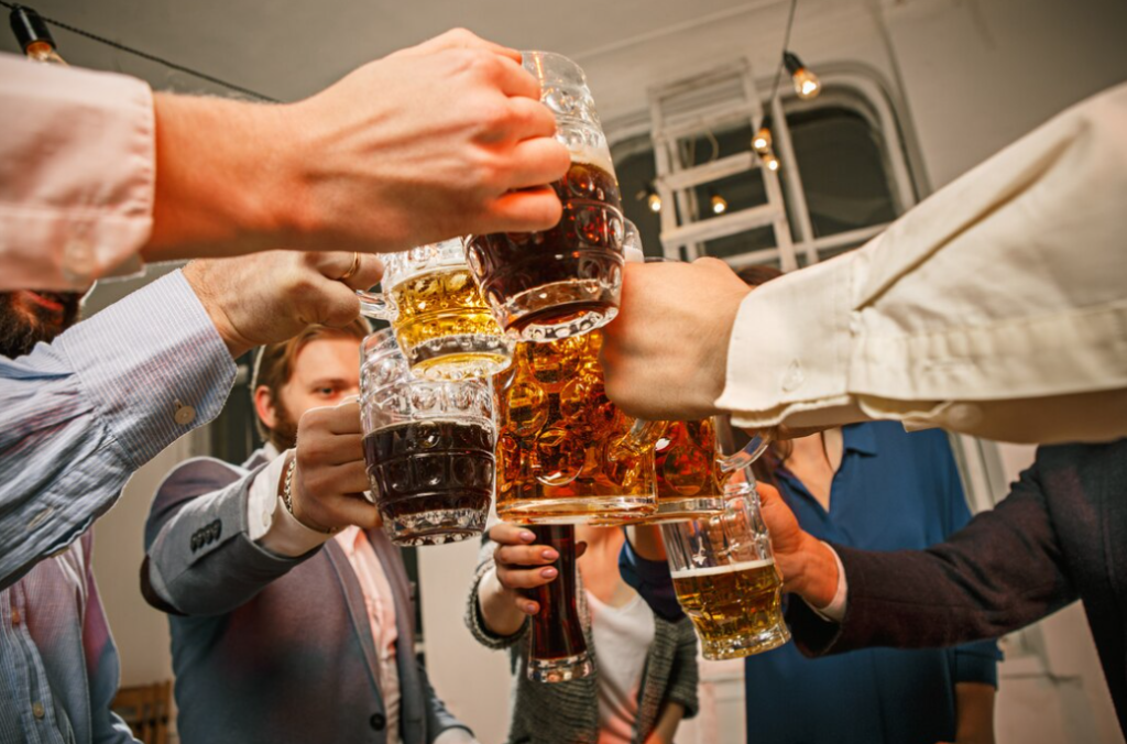 people in classic suits clinking with a glass of beer, the window behind in a white room with lamps 