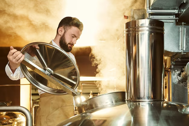 A man holds a lid from a steam keg where beer is prepared