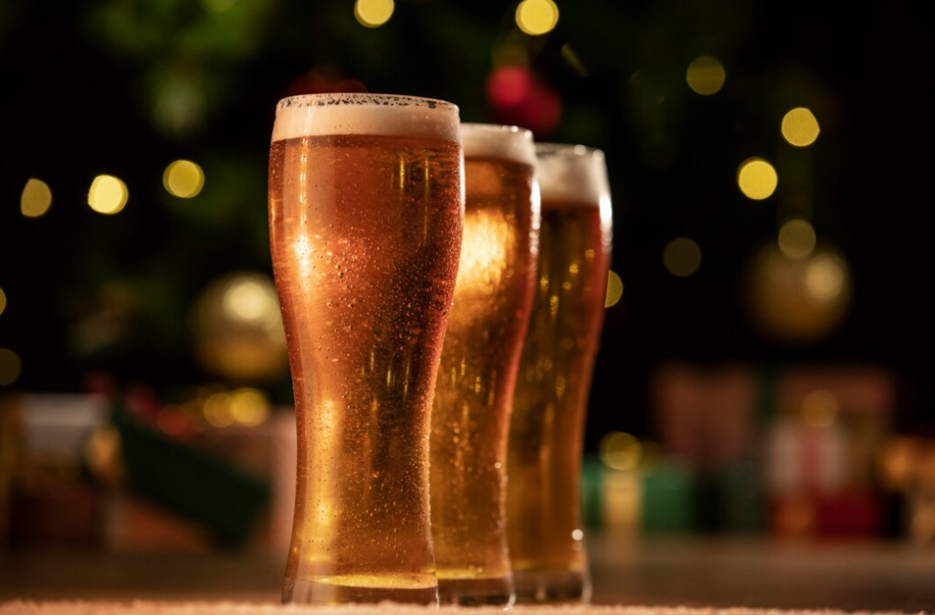 three glasses of beer with foam on the table in a dark room with yellow lights 