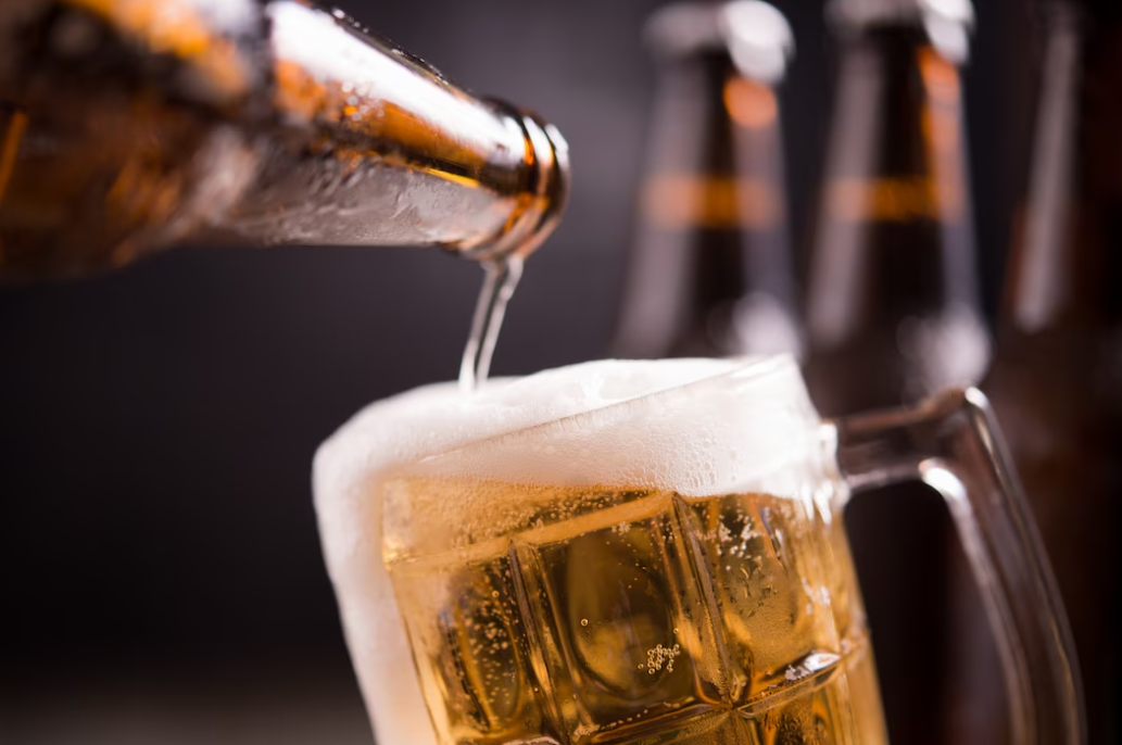 man pouring beer into a glass with one hand and holding beer with another hand