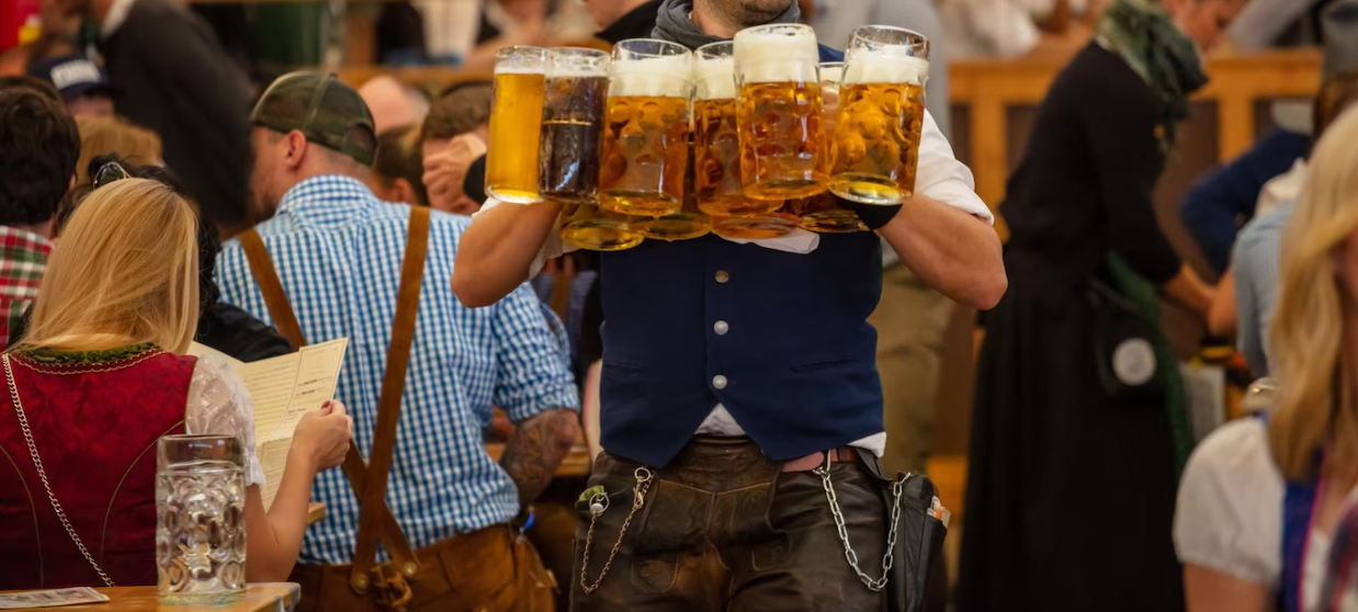 the waiter holds a glass of beer, and people sitting at the table and reading a menu